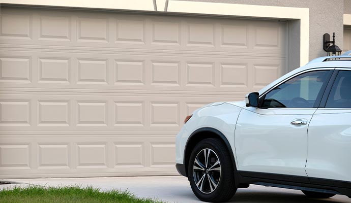 A car parked in front of a beige sectional garage door