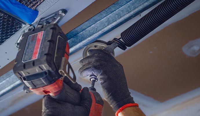 A professional installing garage door spring with equipment