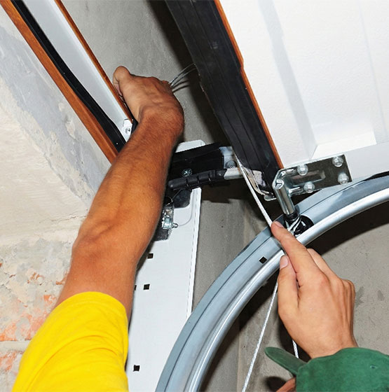 Technician adjusting garage door cable and track