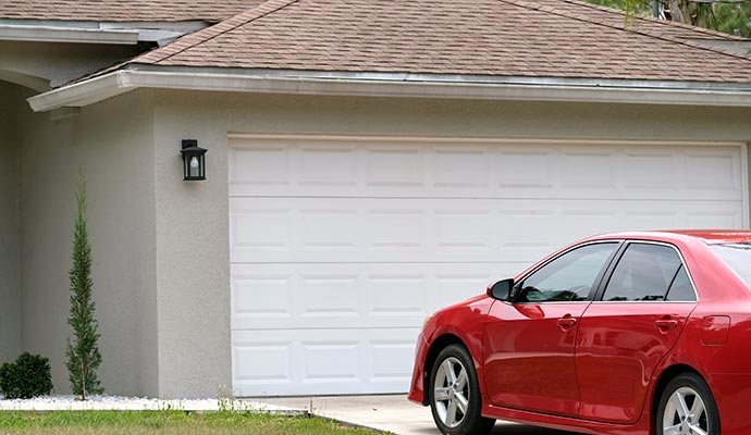 Red car parked in front of a residential garage door